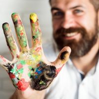 Mann mit Farbe an der Hand